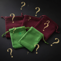 Green and burgundy velvet drawstring pouches on a dark moody background with antique gold question marks