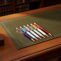 Oil filled dried flower ballpoint pens laid flat on a Regency-style writing desk
